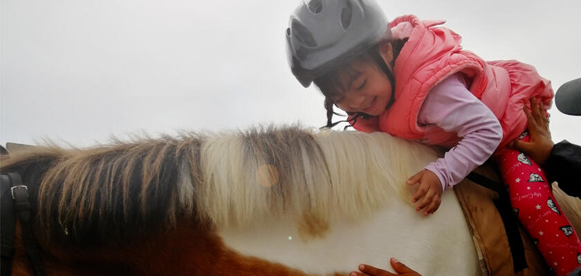 Niña feliz montando el caballo