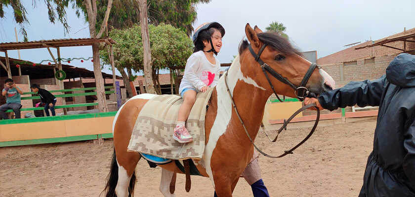 Niña feliz montada en el caballo
